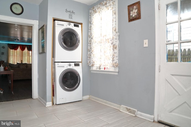 laundry room featuring stacked washer and dryer and plenty of natural light