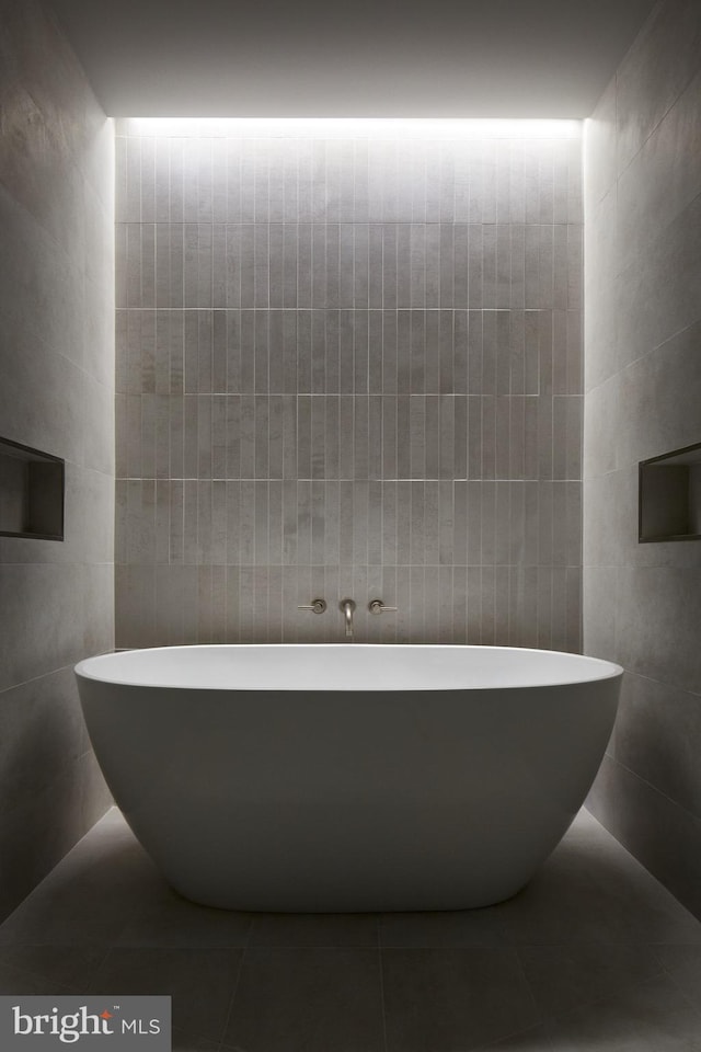 bathroom featuring a tub to relax in, tile walls, and tile patterned floors