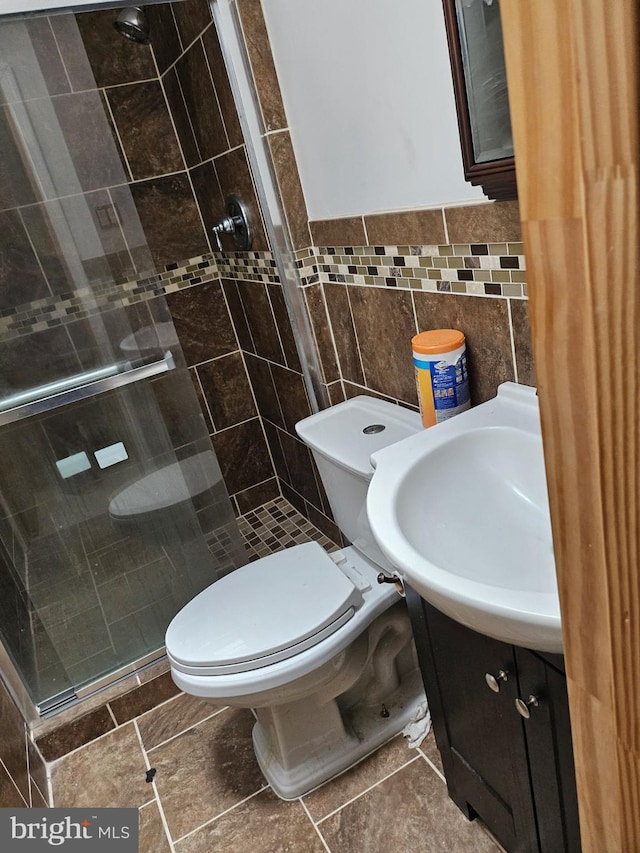 bathroom featuring vanity, tile walls, toilet, and a shower with door