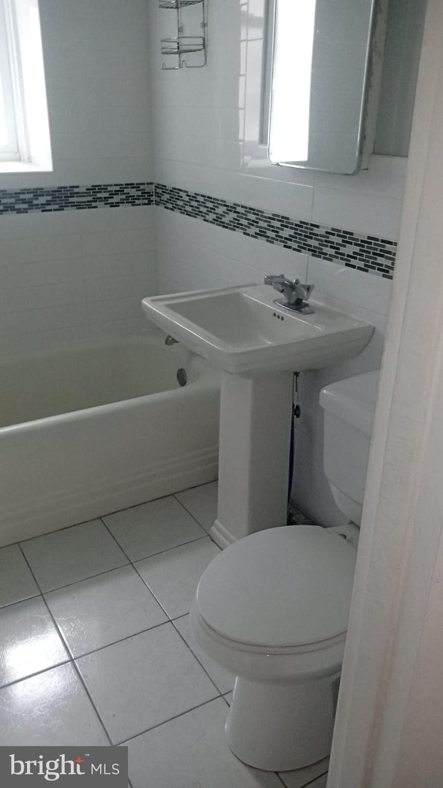 bathroom featuring tile walls, tile patterned flooring, and toilet