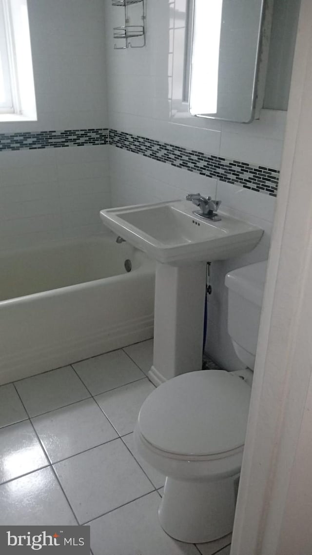 bathroom featuring tile walls, tile patterned flooring, and toilet