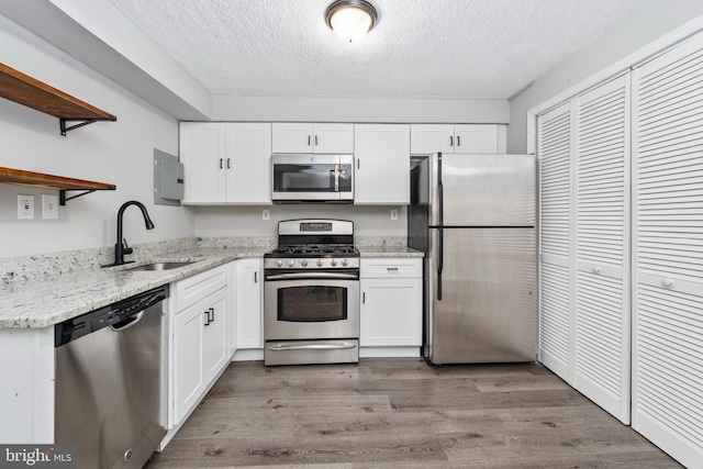 kitchen with a textured ceiling, sink, light hardwood / wood-style flooring, and stainless steel appliances