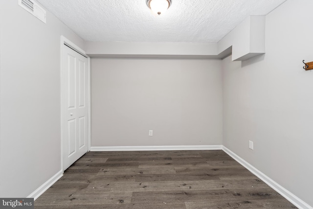 interior space featuring a textured ceiling, a closet, and dark wood-type flooring