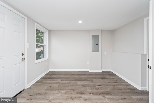 unfurnished room with electric panel and hardwood / wood-style flooring