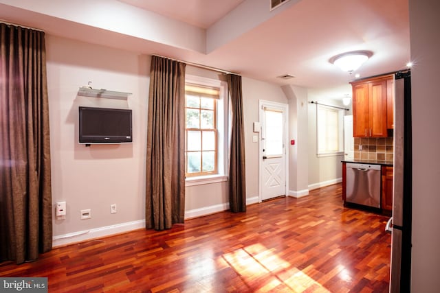 interior space featuring appliances with stainless steel finishes, dark hardwood / wood-style floors, tasteful backsplash, and a barn door