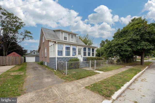 bungalow-style home with an outbuilding, a garage, and a front lawn