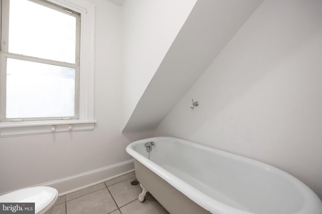 bathroom with a wealth of natural light, tile patterned flooring, a washtub, and toilet