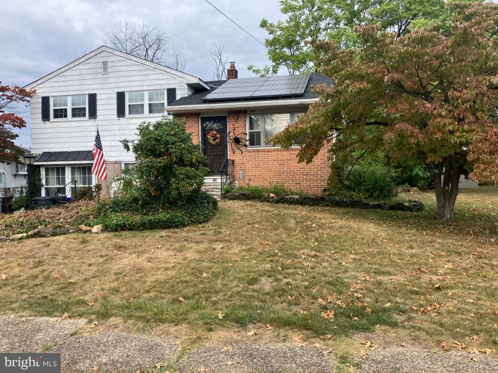 tri-level home with solar panels and a front yard