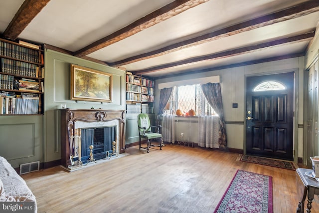 foyer with beam ceiling, wood-type flooring, and a high end fireplace