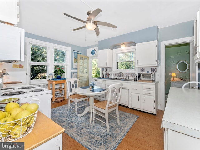 kitchen with white appliances, plenty of natural light, light hardwood / wood-style floors, and white cabinetry