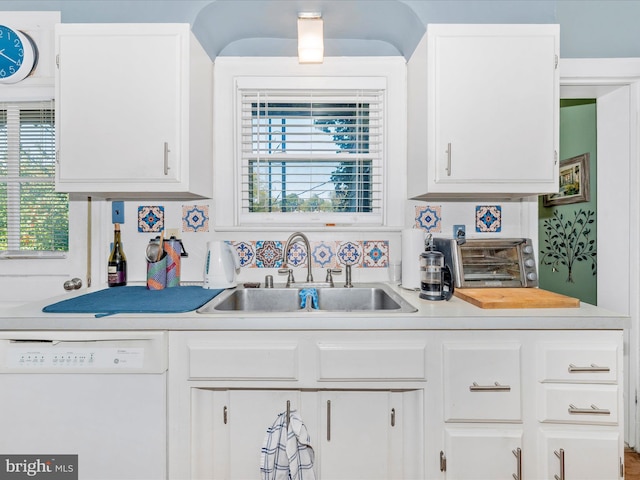 kitchen featuring white dishwasher, a healthy amount of sunlight, sink, and white cabinets