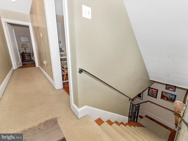 staircase with vaulted ceiling and carpet