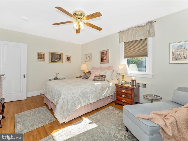 bedroom with wood-type flooring, radiator heating unit, and ceiling fan