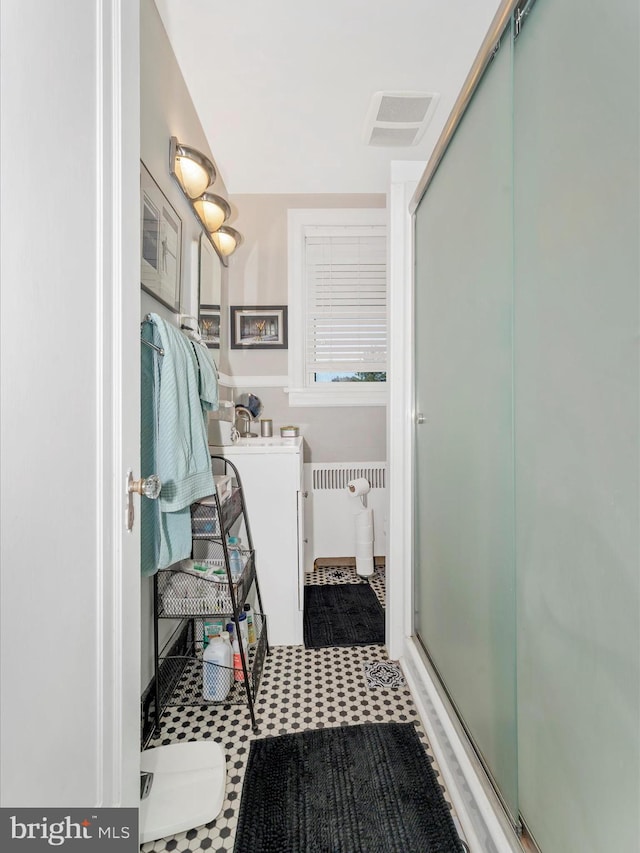 bathroom featuring a shower with door and radiator