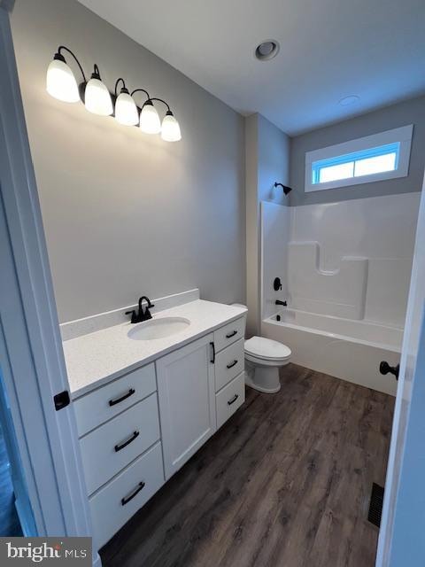 full bathroom with  shower combination, vanity, hardwood / wood-style flooring, and toilet