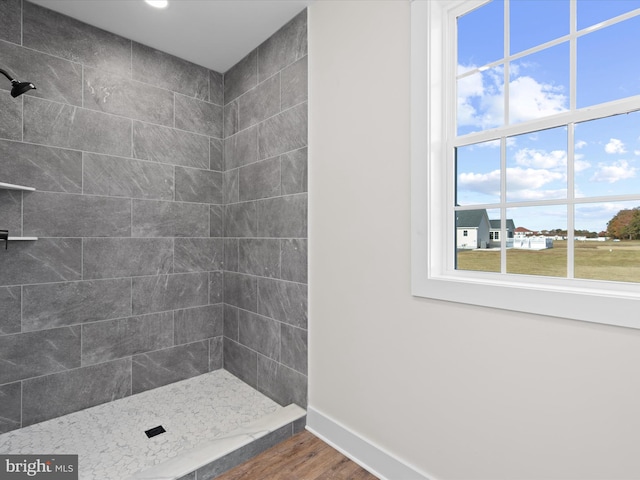 bathroom featuring a tile shower and wood-type flooring