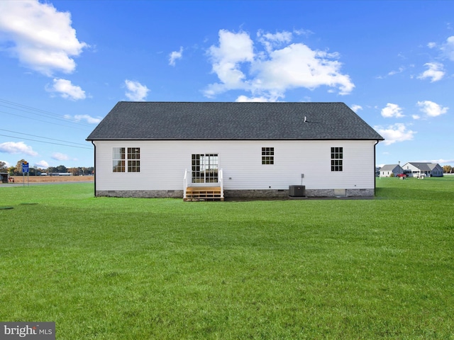 rear view of house featuring central AC and a yard