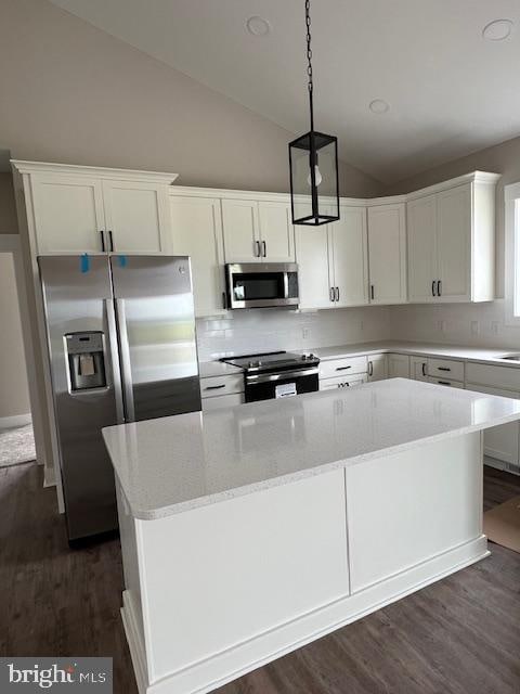 kitchen with lofted ceiling, white cabinets, light stone counters, dark wood-type flooring, and stainless steel appliances