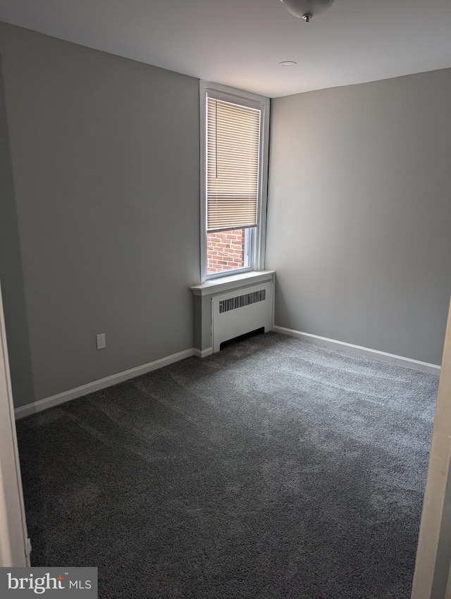 carpeted empty room featuring radiator heating unit