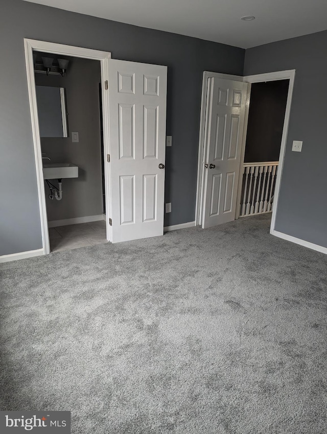 unfurnished bedroom featuring carpet, ensuite bathroom, and sink