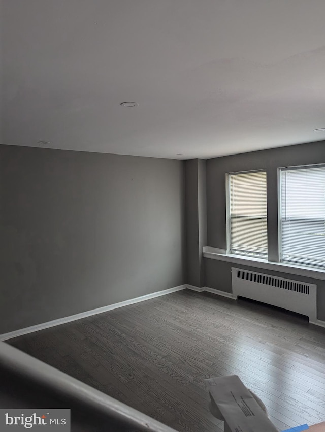 unfurnished room featuring hardwood / wood-style flooring and radiator heating unit