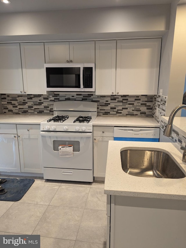 kitchen featuring appliances with stainless steel finishes, sink, light stone counters, and tasteful backsplash