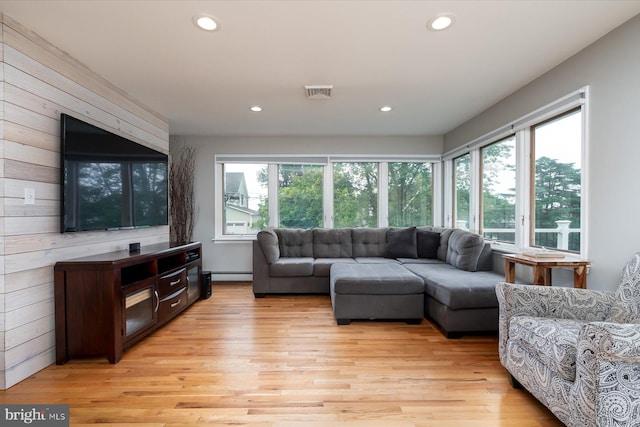 living room with a baseboard heating unit and light wood-type flooring