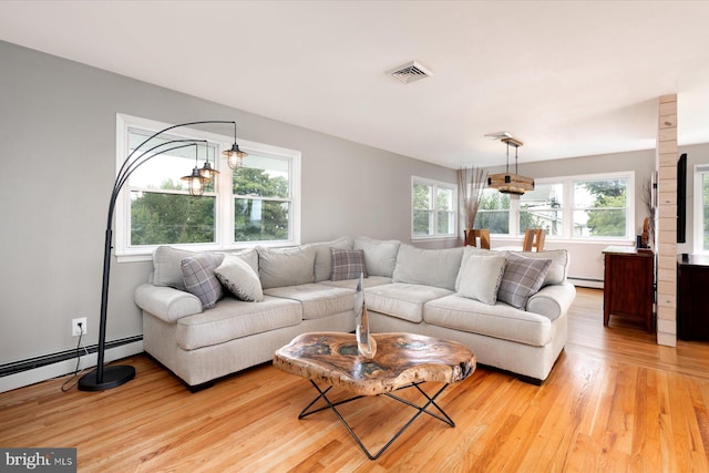 living room featuring baseboard heating, light hardwood / wood-style flooring, and a notable chandelier