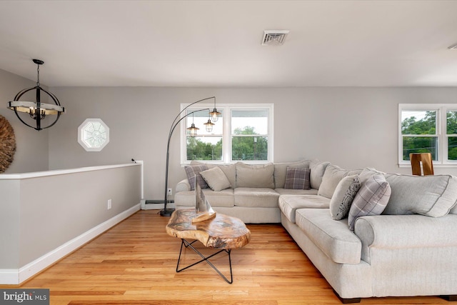 living room featuring a wealth of natural light, light hardwood / wood-style floors, and an inviting chandelier