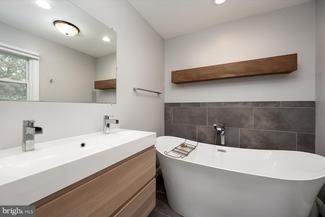 full bathroom featuring a freestanding bath, tile walls, wainscoting, recessed lighting, and vanity
