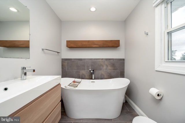 full bathroom featuring recessed lighting, tile patterned floors, vanity, tile walls, and a soaking tub