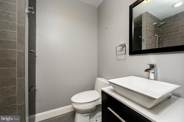 bathroom with vanity, toilet, and tiled shower