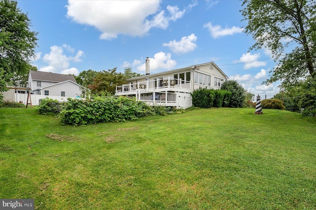 rear view of property featuring a chimney, fence, a yard, and a deck