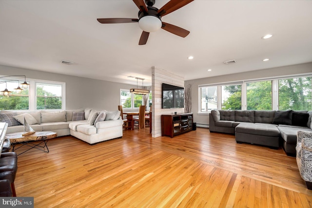 living room with light wood-style flooring, visible vents, a baseboard radiator, and a healthy amount of sunlight