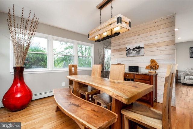 dining room featuring light wood-type flooring, wood walls, recessed lighting, and a baseboard radiator