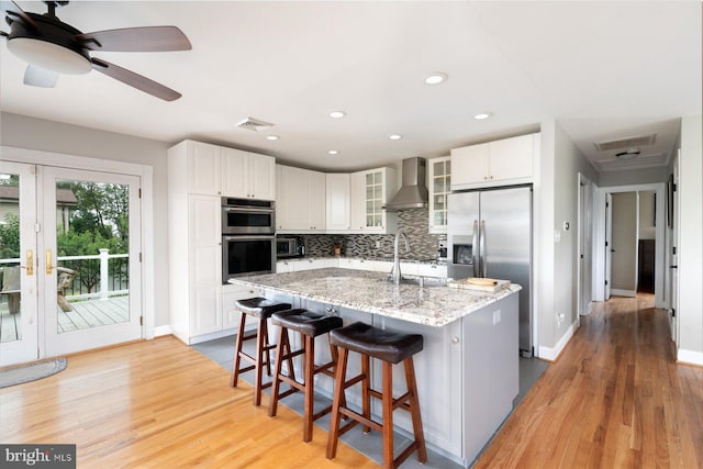 kitchen featuring white cabinetry, appliances with stainless steel finishes, light wood-type flooring, and a kitchen island with sink