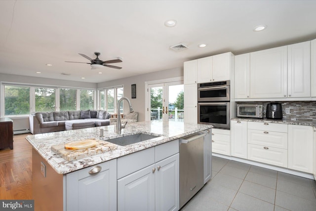 kitchen with a center island with sink, ceiling fan, white cabinetry, sink, and stainless steel appliances