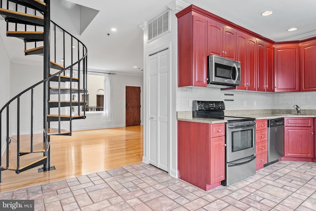 kitchen featuring ornamental molding, stainless steel appliances, backsplash, and light wood-type flooring