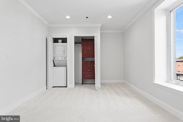 unfurnished bedroom featuring light carpet, stacked washer / drying machine, and multiple windows