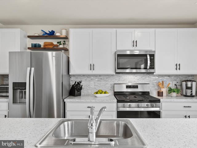 kitchen with light stone countertops, appliances with stainless steel finishes, and white cabinetry