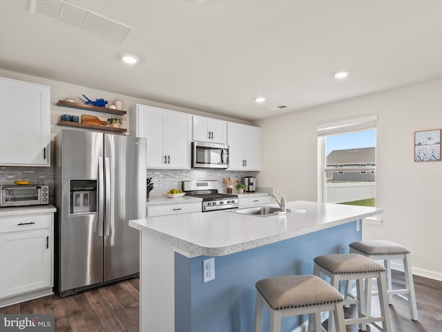 kitchen with white cabinets, sink, a kitchen island with sink, appliances with stainless steel finishes, and dark hardwood / wood-style floors