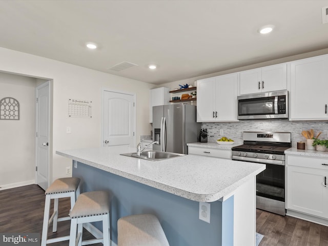 kitchen featuring sink, a kitchen bar, stainless steel appliances, a center island with sink, and dark hardwood / wood-style flooring