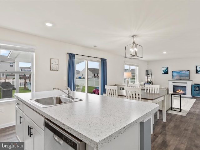 kitchen featuring hanging light fixtures, sink, stainless steel dishwasher, a center island with sink, and dark hardwood / wood-style floors