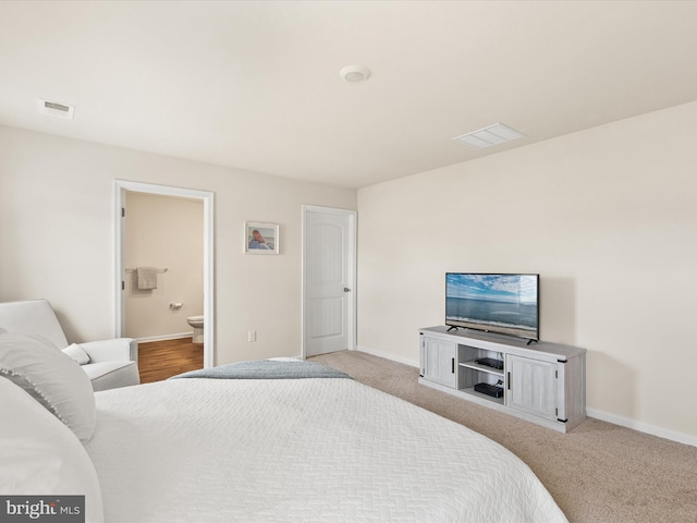 bedroom with light carpet and connected bathroom