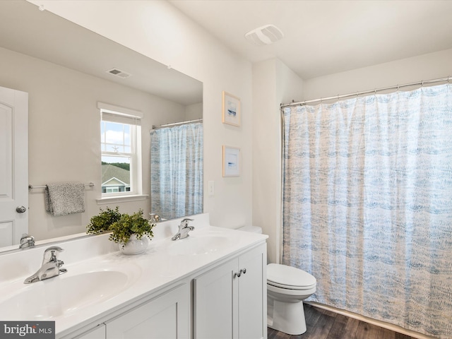 bathroom with wood-type flooring, curtained shower, vanity, and toilet