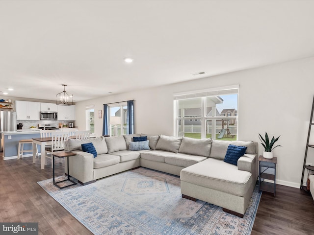 living room with an inviting chandelier and dark hardwood / wood-style flooring