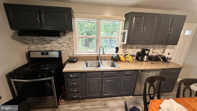 kitchen with tasteful backsplash, stainless steel appliances, light wood-type flooring, sink, and extractor fan