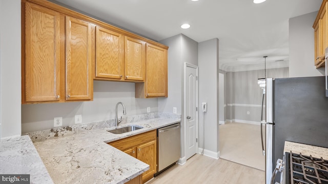 kitchen with sink, light stone countertops, light wood-type flooring, appliances with stainless steel finishes, and decorative light fixtures