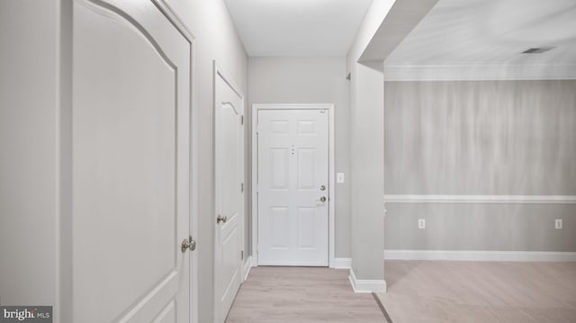 hallway with light hardwood / wood-style floors and ornamental molding