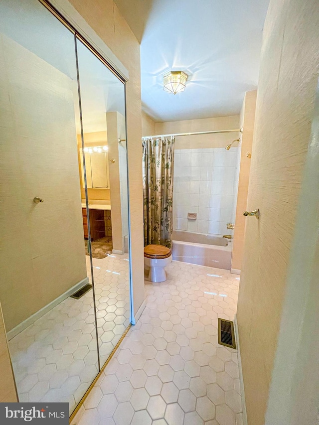 bathroom featuring shower / bathtub combination with curtain, tile patterned flooring, and toilet